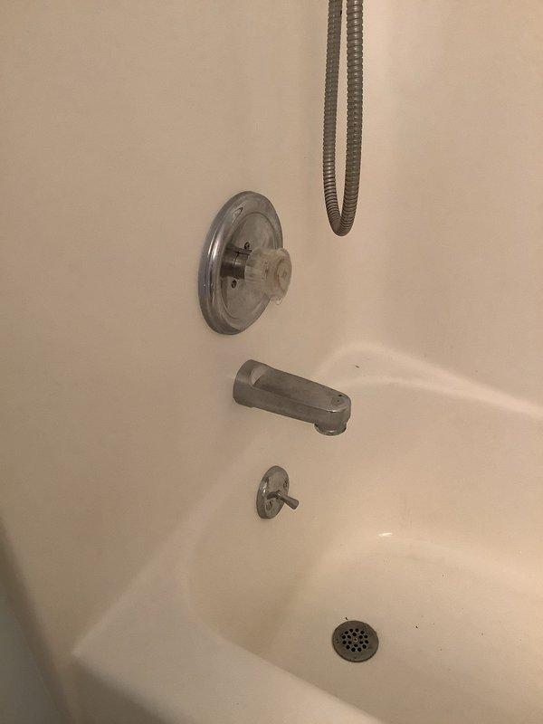 Responded to service call for leaking bathtub faucet. Upon inspection, discovered significant corrosion and mineral buildup on internal drain assembly components, including deteriorated metal brackets and oxidized brass fittings with rust staining around the fixture opening. Assessed all visible plumbing fixtures including tub spout, shower diverter, and drain components to determine source of leak and extent of deterioration requiring repair.