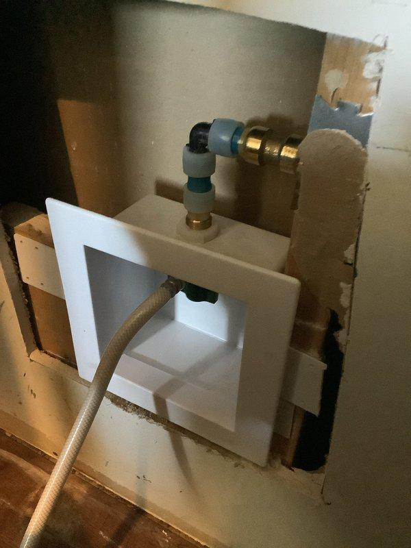 Cut open drywall to access existing water line behind refrigerator. Cut into copper supply line and removed old ice maker outlet box. Installed new ice maker outlet box with compression fittings and reconnected water supply line. Tested connections for leaks and reconnected refrigerator water line. Parts have been ordered for follow-up visit to complete drywall repair and finish work.