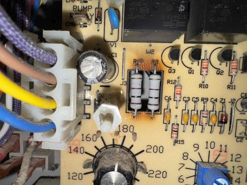 Responded to service call for boiler experiencing intermittent operation, randomly shutting off for extended periods before restarting. Inspected control board and found signs of age-related deterioration with visible discoloration and residue on circuit components. Examined Honeywell temperature control dial and associated wiring connections at pump terminal block, noting multiple wire connections including braided, orange, yellow, and blue leads. Documented condition of control board components including resistors, capacitors, rotary potentiometers, and temperature adjustment dials marked for settings ranging from 120-220 degrees. Recommended monitoring system performance and potential control board replacement due to intermittent failure pattern consistent with aging electronic components.