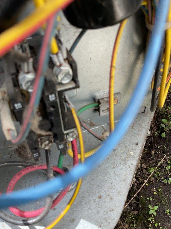 Responded to no cooling complaint on 5-year-old residential air conditioning system with reported refrigerant leak. Performed electrical diagnostics at outdoor condensing unit, measuring amperage draw at contactor assembly which registered 0.58 amps. Inspected electrical connections, capacitor, and contactor components housed in junction box mounted at ground level. Visual inspection revealed weathered outdoor electrical enclosure with multiple wire connections showing signs of age and environmental exposure. Documented system conditions and electrical measurements for repair estimate preparation.