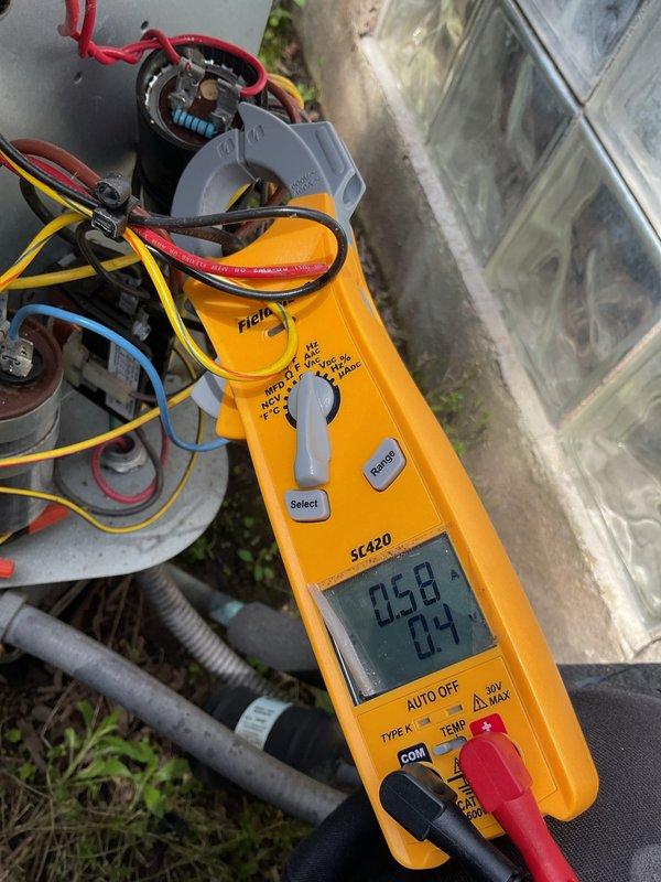 Responded to no cooling complaint on 5-year-old residential air conditioning system with reported refrigerant leak. Performed electrical diagnostics at outdoor condensing unit, measuring amperage draw at contactor assembly which registered 0.58 amps. Inspected electrical connections, capacitor, and contactor components housed in junction box mounted at ground level. Visual inspection revealed weathered outdoor electrical enclosure with multiple wire connections showing signs of age and environmental exposure. Documented system conditions and electrical measurements for repair estimate preparation.