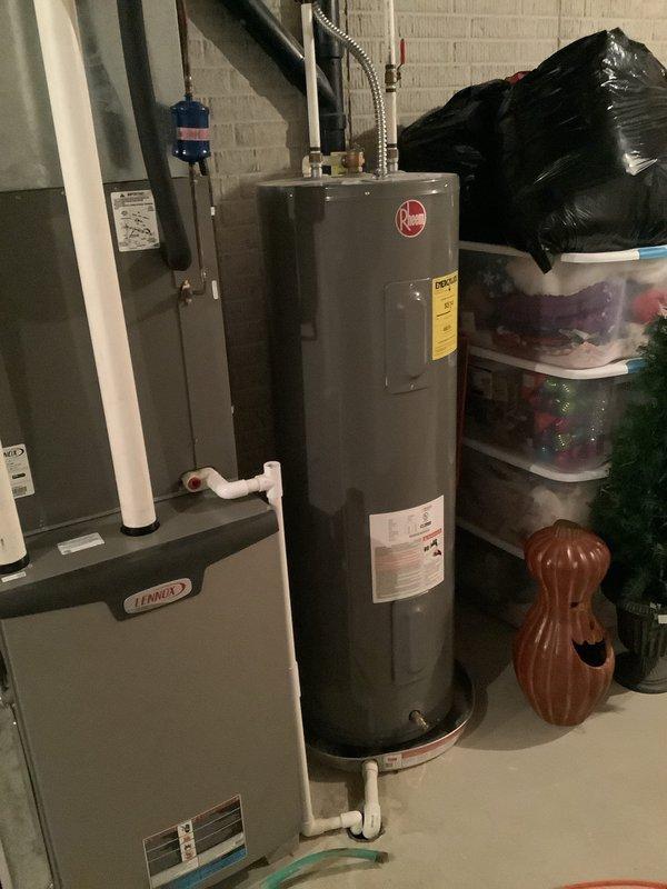 Performed comprehensive inspection of 13-year-old Rheem water heater in basement utility area. Unit evaluated for operational status, proper venting configuration with white PVC piping, temperature and pressure relief valve function, and overall condition of connections and components. Documented existing installation with photographs showing water heater positioned adjacent to Lennox furnace, proper clearances maintained, and standard plumbing connections at base of tank including flexible metallic supply lines and white PVC discharge piping.
