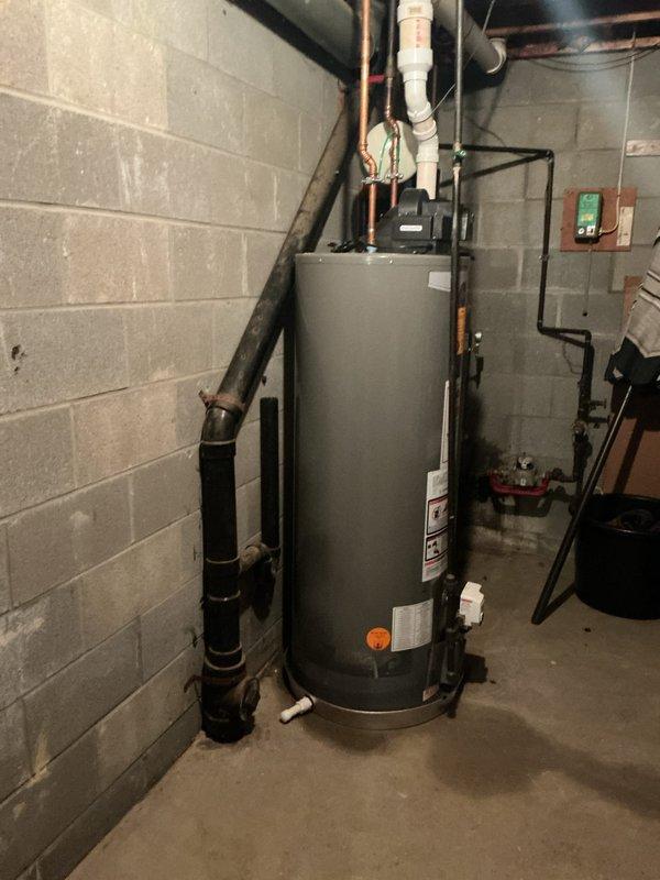 Responded to service call for leaking 6-year-old Rheem Performance tanked water heater in basement utility area. Upon inspection, identified active leak on unit and assessed water heater condition along with associated plumbing connections including copper supply lines, PVC piping, and pressure relief valve configuration. Documented equipment installation with photographic evidence showing water heater positioning, piping arrangement, and electrical connections for service records and future reference.