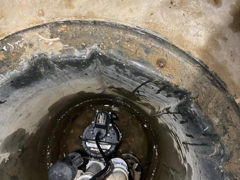 Replaced two check valves in stormwater sump pit system and installed new 1/2 HP primary sump pump. The existing sump basin showed significant mineral deposits and staining from groundwater management operations. Removed failed pump and check valves, installed replacement equipment with proper PVC discharge piping connections, and verified system operation with standing water test. All electrical connections secured and pump cycling tested successfully.