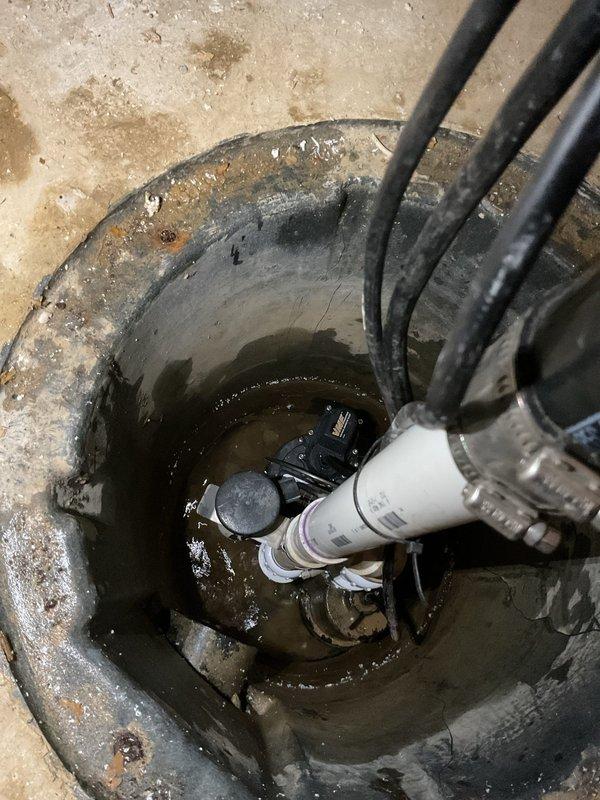 Replaced two check valves in stormwater sump pit system and installed new 1/2 HP primary sump pump. The existing sump basin showed significant mineral deposits and staining from groundwater management operations. Removed failed pump and check valves, installed replacement equipment with proper PVC discharge piping connections, and verified system operation with standing water test. All electrical connections secured and pump cycling tested successfully.