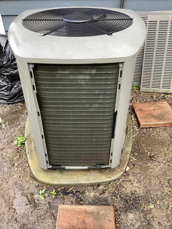 Completed MVP recurring maintenance visit on residential cooling system. Inspected outdoor condenser unit, which showed moderate accumulation of debris in heat exchanger coils with visible discoloration and dirt buildup between fin rows. Unit operational with fan assembly and protective grilles intact. Noted environmental debris around base including leaves and organic matter on surrounding soil. Condenser pad exhibited minor weathering and surface growth consistent with age. All major components visually confirmed functional during inspection.