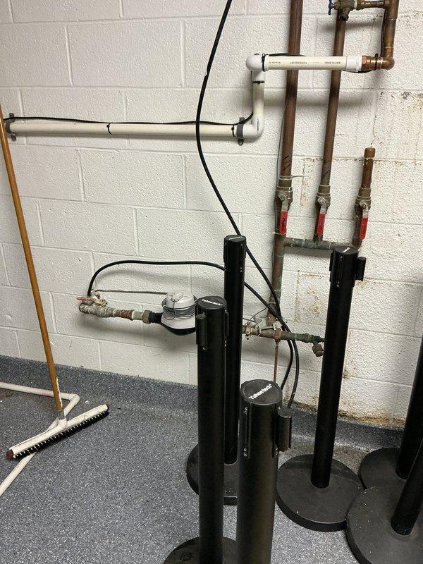 Responded to service call for potential water heater replacement in a fifteen-year-old residence. Upon arrival, inspected existing dual water heater installation in basement utility area. Documented current plumbing configuration including copper pipe connections, shut-off valves, and water treatment components. Assessed condition of both gray cylindrical water heaters mounted on concrete block wall, noting connection points, valve accessibility, and overall system layout. Photographed existing installation including supply and discharge piping, electrical connections, and surrounding utility space to provide comprehensive documentation for replacement estimate.