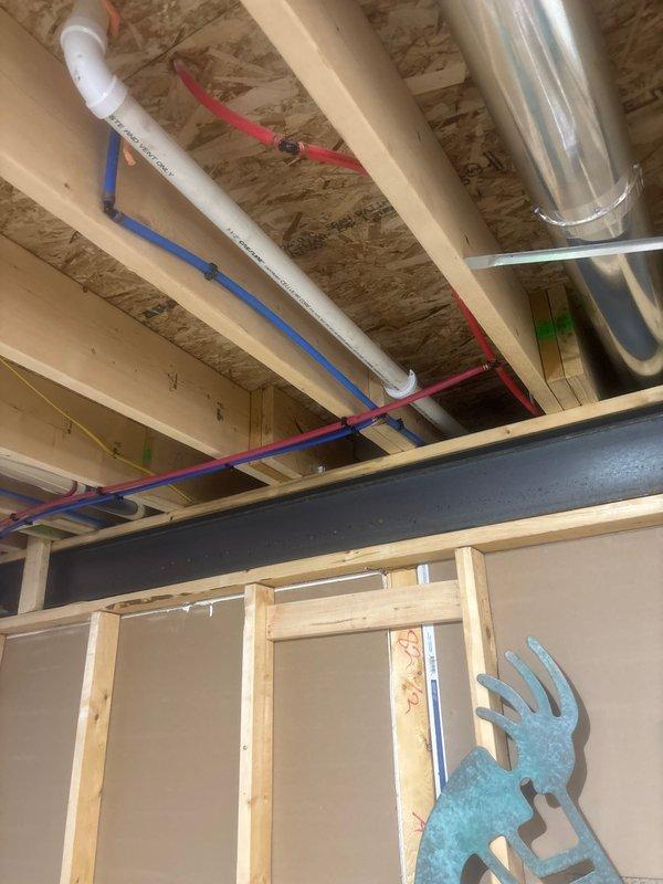 Installed customer-supplied laundry sink in utility room by tying into main stack with 4x2 wye fitting and running drain line to sink location with P-trap for code compliance. Cut into existing hot and cold water lines and ran approximately 20 feet of PEX tubing with new shutoff valves, secured with tube talons. Anchored laundry sink to floor, connected chrome faucet fixture, and verified proper drainage and water supply functionality.