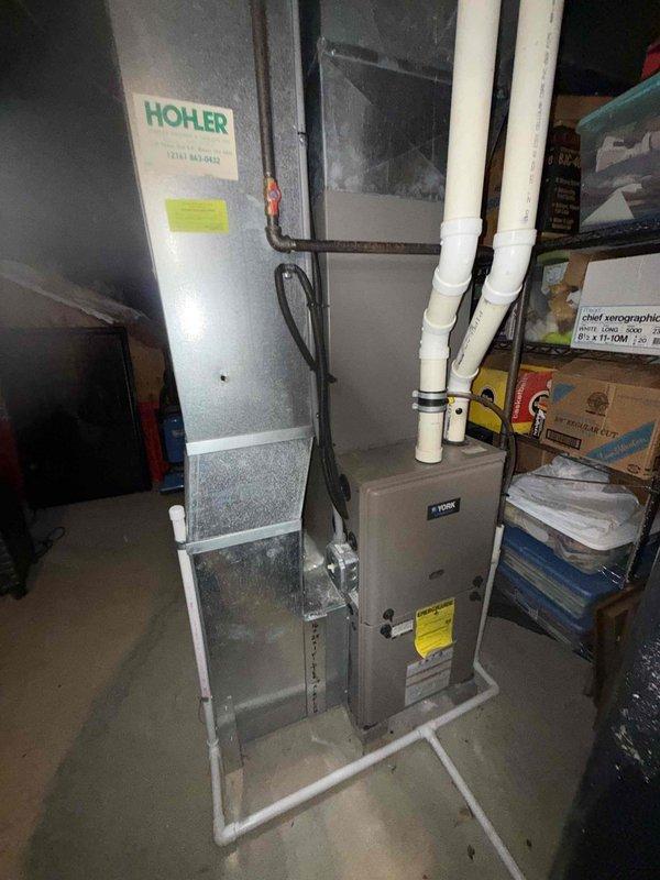 Completed BS-MVP preventive maintenance cooling visit on 3-year-old residential air conditioning system. Inspected York furnace and Hohler air handler unit in basement mechanical room, verified proper operation of all components, checked refrigerant levels, tested electrical connections, and cleaned condensate drain lines. Noted dust accumulation on return air grille and recommended filter replacement to maintain optimal system efficiency and indoor air quality.