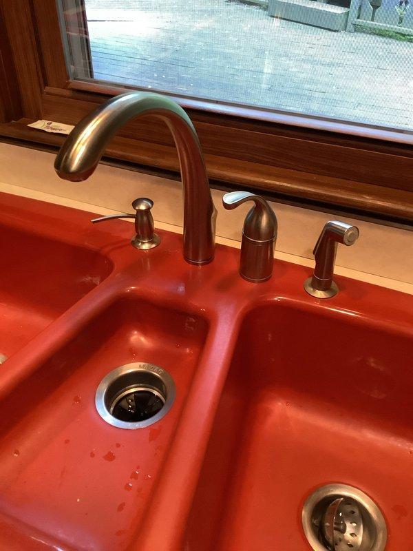 Responded to service call for leaking faucet on double-basin kitchen sink. Upon inspection, identified leak originating from supply line connections beneath the Kohler fixture. Tightened braided flexible supply hoses at connection points and verified proper sealing of fittings. Tested faucet operation across both basins, confirmed leak was resolved, and left fixture in proper working condition.