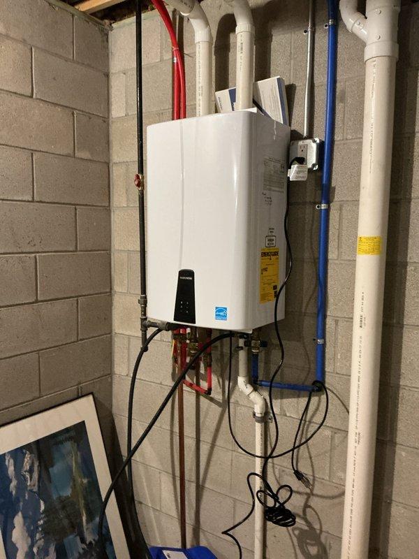 Performed routine maintenance flush on wall-mounted Navien tankless water heater unit located in basement utility room. Completed descaling procedure to remove mineral buildup from heat exchanger and internal components, then refilled system and verified proper operation. Unit returned to normal service with all connections secure and operational parameters confirmed.