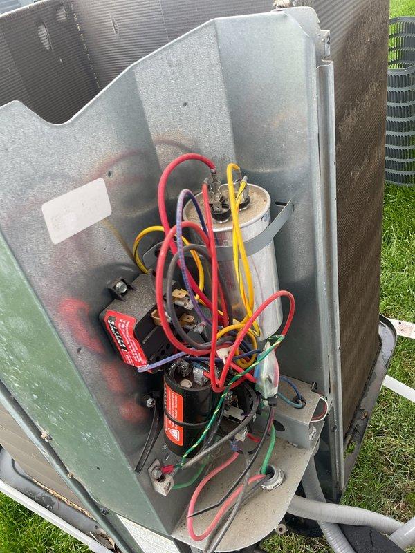 Completed MVP cooling maintenance visit on residential air conditioning system. Upon inspection, found substantial dirt, dust, and debris accumulation on condenser coils with thick buildup of fibrous material along the top edge of fins, restricting airflow and reducing heat transfer efficiency. Accessed internal compartment to inspect electrical components including capacitor, compressor connections, and associated wiring. All electrical connections verified secure with proper wire routing observed. Documented pre-service condition of heavily soiled condenser coils and internal component configuration through photographic evidence. Unit showed signs of extended operation without routine maintenance based on level of contamination present on heat exchange surfaces.