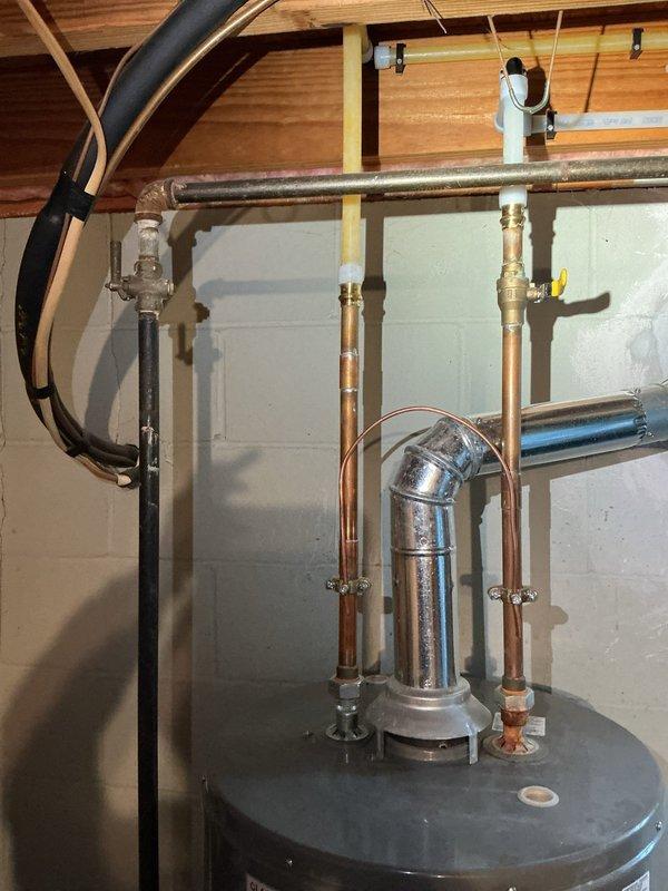 Responded to service call for leaking tanked water heater in residential basement. Upon arrival, performed comprehensive assessment of existing water heater system and surrounding plumbing connections. Inspected copper supply lines, brass shutoff valves, temperature and pressure relief valve, and all associated piping for signs of deterioration and active leaks. Documented current installation configuration including hot and cold water distribution lines, galvanized steel cross-connections, and proper venting arrangements. Examined floor area surrounding unit and confirmed active water leakage from tank, indicating internal tank failure. Photographed existing plumbing setup showing multiple copper pipe connections, brass ball valves with handles, metallic elbow joints, and mounting hardware attached to ceiling joists. Prepared detailed estimate for complete water heater replacement including removal of failed unit, installation of new tanked water heater with proper code-compliant conn