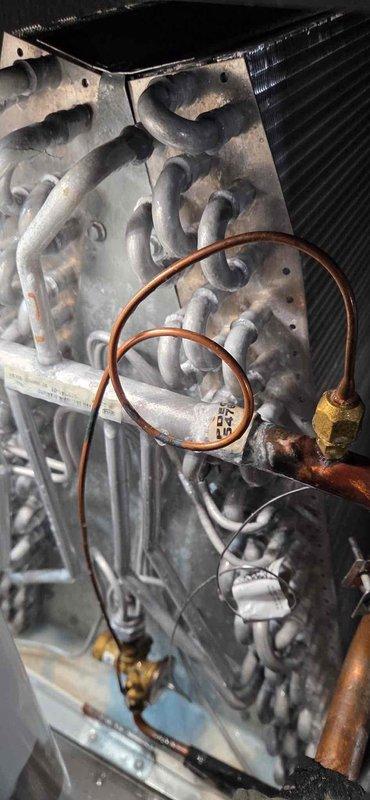 Rescheduled service visit due to previous weather conditions preventing proper leak search procedures. Upon arrival with suitable weather conditions (60 degrees, no precipitation), inspected HVAC system components including heat exchanger assembly, evaporator coil, copper refrigerant lines, and condenser unit. Documented equipment condition showing signs of extended use with oxidation and residue buildup on heat exchanger surfaces. Photographed system components including coiled copper tubing with brass fittings, finned coil assembly, and associated piping. Leak search procedure to be completed during this return visit under appropriate environmental conditions for accurate detection.