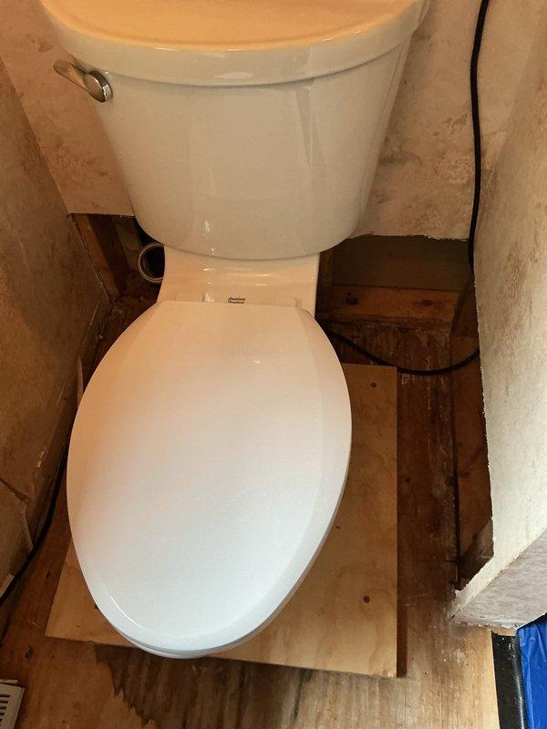 Removed existing round bowl toilet and replaced with American Standard Champion elongated bowl model, upgraded to chair height configuration at 16.5 inches for improved accessibility. Installation completed on plywood subfloor in bathroom undergoing renovation, with new water supply line connected and all plumbing connections secured and tested for proper operation.