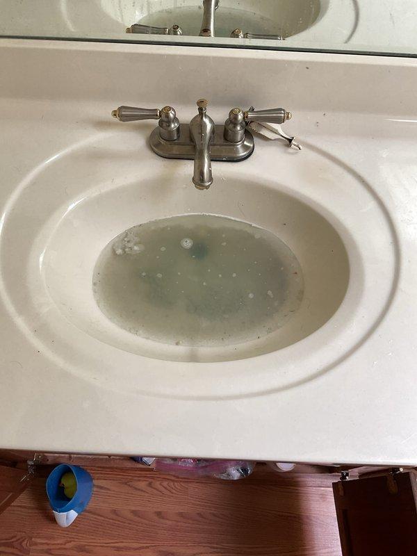 Responded to service call for three clogged sink drains on the second floor that were slowly draining. Upon arrival, found bathroom sink with standing water containing visible debris and particles, indicating drainage obstruction. Assessed plumbing system and cleared blockages from affected drain lines using appropriate tools and techniques. Verified proper water flow and drainage function was restored to all three sinks. Removed debris and tested fixtures to ensure complete resolution of the clogging issue.
