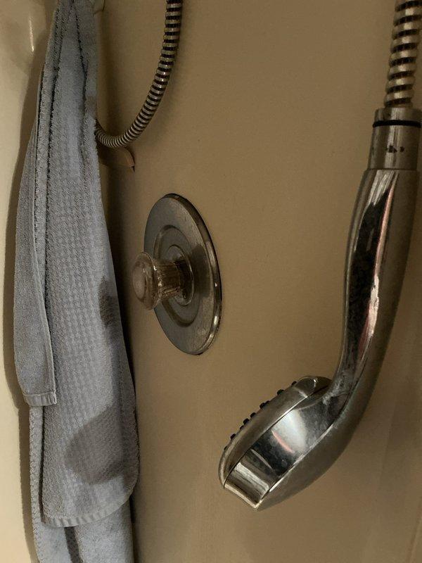 Responded to emergency water leak in downstairs bathroom of 28-year-old home. Upon arrival, main water supply had been shut off by homeowner due to active leak that began the previous evening. Identified source of leak at shower valve assembly behind wall-mounted chrome fixtures. Accessed plumbing through basement/crawlspace area beneath bathroom to assess extent of damage and confirm leak origin. Repaired failed connection at shower diverter valve, replaced worn rubber washers and seals, and tightened compression fittings on supply lines. Verified all flexible supply hoses and brass fittings were properly secured with metal clamps. Restored water supply to home and tested shower valve operation under full pressure to confirm leak was eliminated. No water damage observed to surrounding framing or subfloor materials.