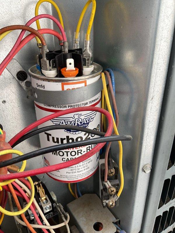 Responded to no cooling complaint on 14-year-old rooftop air conditioning unit. Accessed unit via ladder and crawlspace. Upon inspection, found failed motor-run capacitor preventing compressor operation. Removed access panel and inspected electrical components. Replaced defective Amrad Turbo 200 capacitor with new unit, reconnected all electrical terminals, and verified proper wire connections. Tested system operation and confirmed compressor startup and normal cooling function restored. Secured access panel and left unit operational.