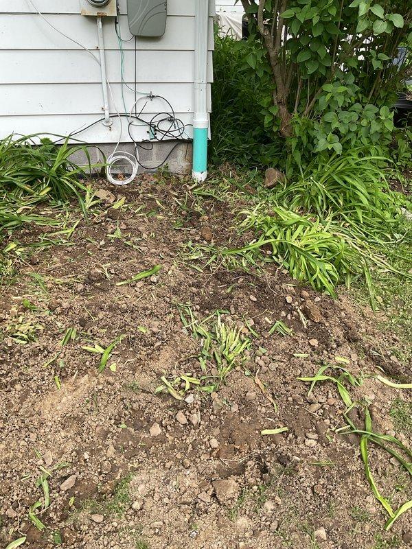 Excavated and replaced existing underground downspout drainage line on right side of residential property from rear roof leader to city connection point. Connected existing underground downspout from sunroom roof leader to new drainage system. Relocated sump pump discharge from underground to above-grade installation and integrated into downspout drainage system. Verified proper pitch throughout entire drainage line to ensure adequate water flow and drainage performance. Backfilled excavated areas and mounded soil to accommodate natural settling. All PVC drainage piping installed to code specifications with appropriate fittings and connections at roof leader tie-in points and city connection terminus.