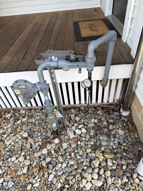 Installed a new 1 1/2" gas main from the exterior meter location under the porch to the interior of the home, establishing supply infrastructure for multiple appliances. Ran gas line to range top with shutoff valve and flex connector installation at kitchen location. Installed 1" gas line under porch extending to rear of property, trenched underground from porch to detached garage/barn structure, then ran line vertically up exterior wall and through attic space to opposite end of building for future heating system connection. Configured multiple future tap points under porch for water heater, furnace, oven, floor heating system, pool heater, and outdoor grill. Completed all pipe fitting installations including reducers, 90-degree elbows, and necessary connections using galvanized materials. All work performed to code specifications with proper meter integration and pressure regulation components in place.