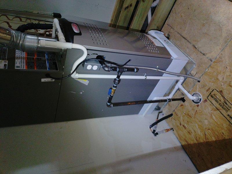 Completed reinstallation of tankless water heater venting system and furnace condensate drain line in attic space. Rerouted white PVC condensate piping from furnace unit to ensure proper drainage and code compliance, and reconfigured black flexible venting connections for the tankless system to achieve optimal exhaust flow and safety clearances.