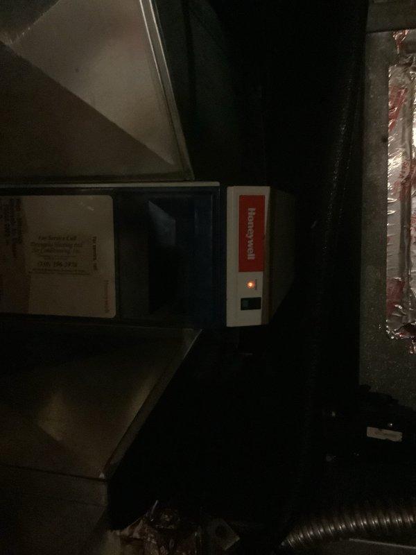 Responded to service call for 15-year-old geothermal system reported as not working. Upon inspection, verified the primary geothermal unit was operational; the issue was isolated to the air purification system's indicator light not functioning. Examined the Honeywell air purification control unit mounted in the mechanical space and confirmed the system power status through visual inspection of equipment components and connections.