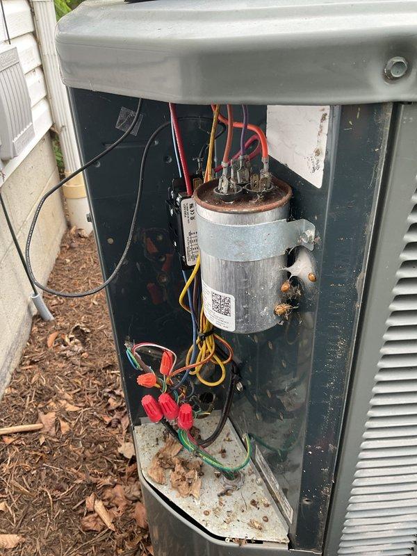 Responded to service call for non-operational AC condenser affecting entire home on 14-year-old system. Upon inspection, identified failed dual-run capacitor with visible rust and corrosion on mounting bracket and terminals. Replaced defective capacitor with new unit, verified proper electrical connections, and tested system operation. Unit restored to full functionality with condenser fan and compressor operating within normal parameters.