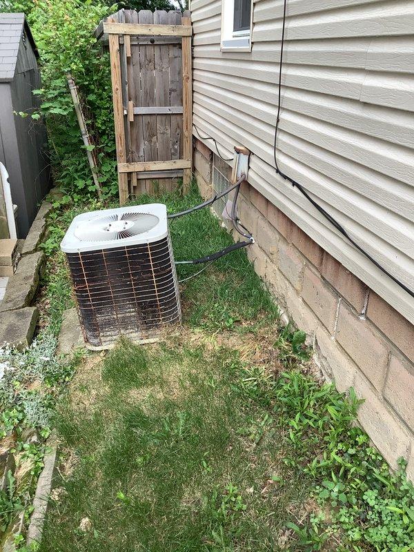Completed installation of new air conditioning system including outdoor condenser unit and indoor evaporator coil. The outdoor condenser was positioned in the side yard with proper clearance from the building, refrigerant lines were run up the exterior wall, and electrical connections were completed. Inside the basement, the new evaporator coil was integrated with the existing furnace system, with PVC condensate drain lines properly routed and secured to prevent water damage.