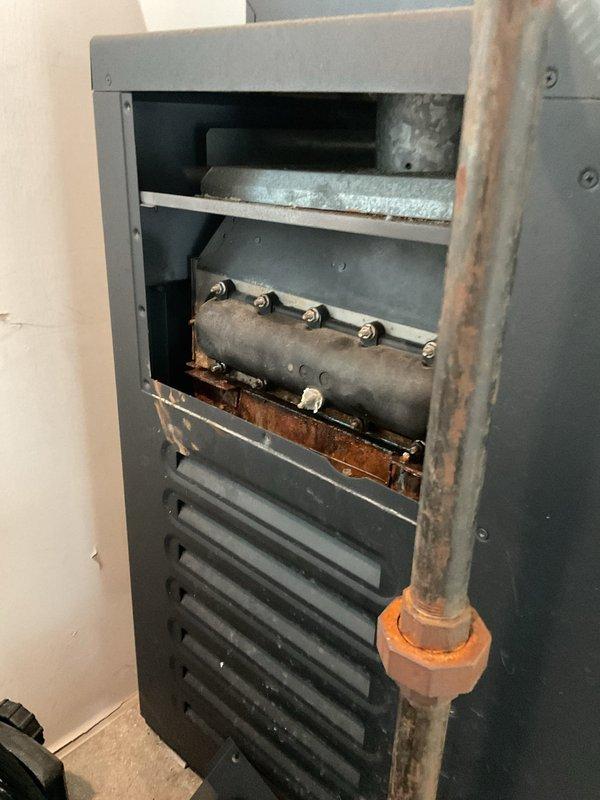 Responded to service call for 9-year-old Rheem heat pump system with reported leaking concerns. Upon inspection, discovered significant rust and corrosion on internal burner assembly and gas manifold components, with visible rust staining on interior metal surfaces beneath the affected areas. Documented existing condition through photographs showing deteriorated cylindrical burner component with brass valve stems and orange-brown rust discoloration throughout the combustion chamber area. Advised customer of findings and potential need for follow-up service to address corrosion issues and prevent further system degradation.