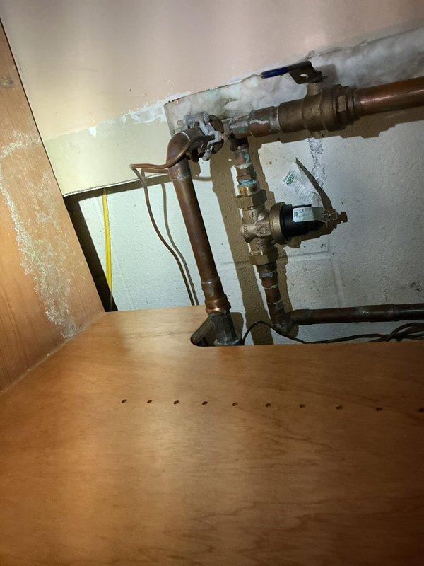 Conducted consultation visit for automatic shut-off valve installation at a 1998-built residential property. Inspected existing copper water supply lines located within cabinet enclosure, noting aged plumbing with existing brass shutoff valves and deteriorating pipe insulation. Assessed installation requirements, discussed valve placement options with homeowner, and provided information regarding automatic shut-off valve systems and installation specifications for future service scheduling.