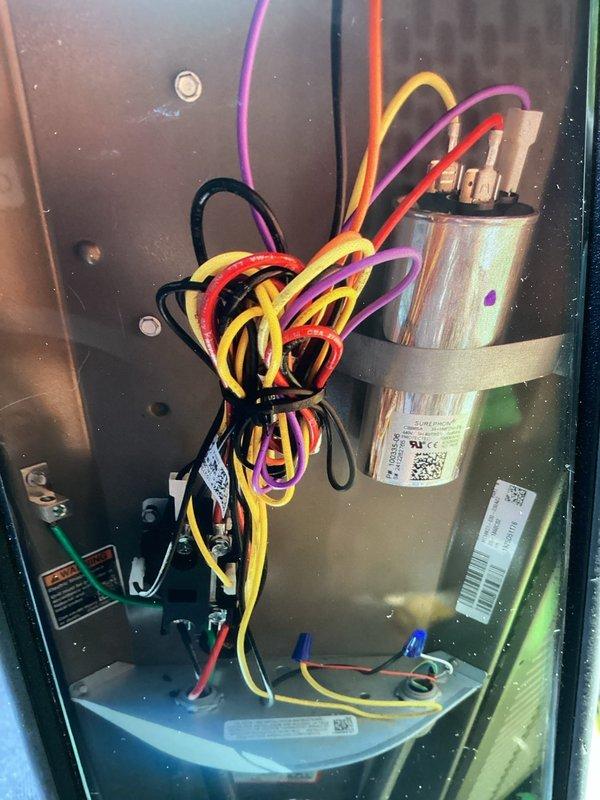 # HVAC Service Report

Responded to no-cooling complaint on newly installed air conditioning system. Upon arrival, performed visual inspection of both indoor and outdoor equipment. Examined indoor unit components including capacitor, motor assembly, and electrical connections. All wire connections were properly secured and labeled per manufacturer specifications. Inspected outdoor condenser unit positioned against building exterior, noting proper clearances and mounting. Verified electrical disconnect and conduit installation. Unit appeared to be correctly installed with appropriate airflow through louvers and fan grille. Diagnostic testing revealed system operational issue related to new installation startup. Addressed cooling deficiency and restored proper system operation. Equipment now functioning within normal parameters.