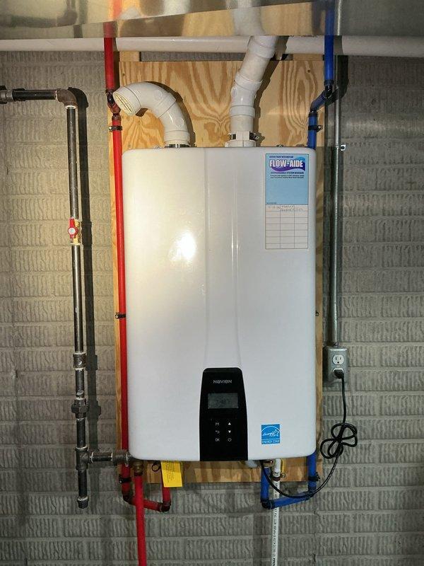 Responded to service call for Navien NPE-240A2 tankless water heater not producing adequate hot water throughout the system. Performed diagnostic evaluation of the unit, inspected all water and gas connections, verified proper venting configuration, and assessed digital control panel operation. Confirmed proper installation of hot and cold PEX supply lines and exhaust venting system, documented unit specifications and current operational status through photographs for service records.
