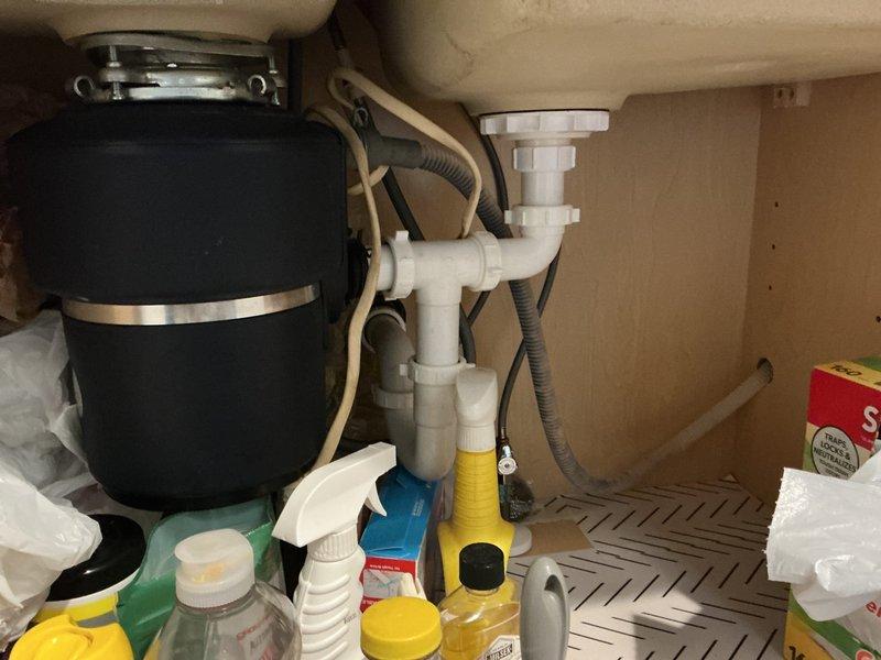 Responded to service call for inspection of main water shut-off valve, exterior spigot, and dishwasher supply line connection under kitchen sink. Assessed seized shut-off valve with inoperable knob to prevent potential damage from forced operation. Inspected dishwasher supply hose connection at sink base, garbage disposal unit, and associated PVC drain assembly. Examined appliance water supply lines including braided flex lines and valve connections. Documented existing plumbing configuration and provided recommendations for valve replacement and connection repairs to restore proper water control functionality.