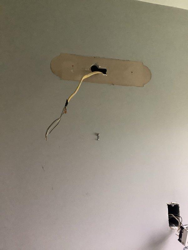 Installed new electrical outlet in bathroom wall to provide power for light fixture. Accessed existing electrical circuit through ceiling, ran appropriate wiring to outlet location, and installed junction box with proper connections. Patched and secured all ceiling and wall openings per code requirements.
