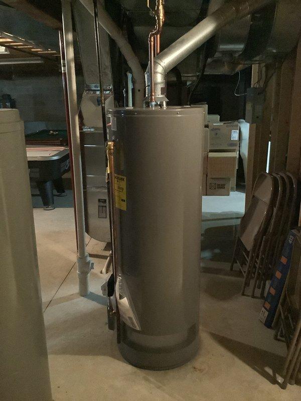 Responded to water leak service call for hot water tank pooling water in basement. Upon arrival, inspected the natural gas water heater and surrounding area, identifying the source of water accumulation on the concrete floor. Assessed the unit's condition, checked all plumbing connections, and documented the installation with photographs showing the cylindrical water heater, copper supply lines, and basement utility configuration. Service completed during standard business hours with MVP membership applied.