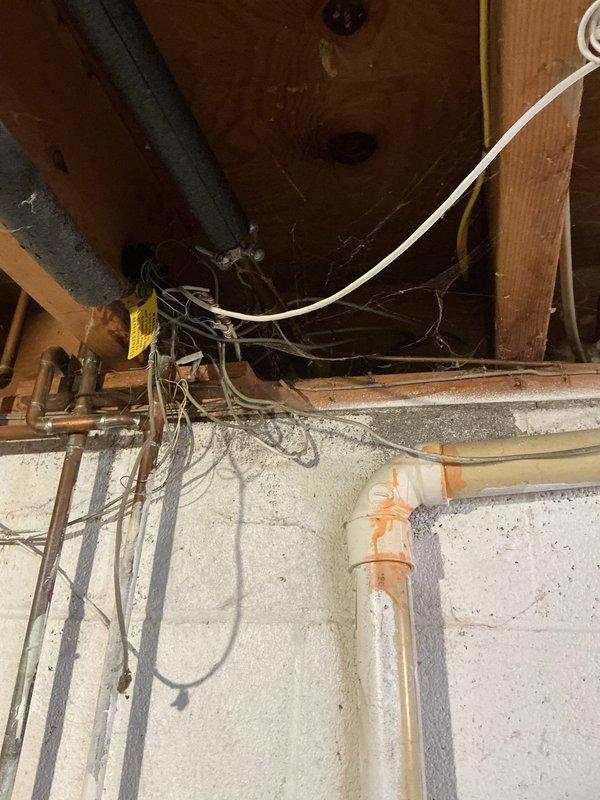 Replaced deteriorated outdoor spigot faucet on 50-year-old residential property. Accessed supply line from basement crawl space, disconnected existing copper piping with visible oxidation and age-related corrosion, and installed new frost-proof sillcock with proper grade for drainage. Verified water flow and tested for leaks at connection points and exterior mounting location near air conditioning condenser unit.