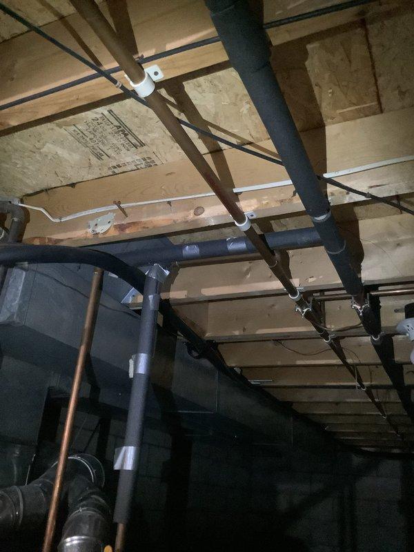 Conducted on-site assessment of existing residential tanked water heater system to provide replacement options. Inspected current gray cylindrical water heater unit located in basement utility area alongside furnace equipment. Documented water heater condition, noting visible moisture staining and discoloration on concrete floor surrounding base of unit, indicating potential minor leakage or condensation issues. Evaluated existing copper supply and distribution piping configuration extending from top of unit. Assessed installation space constraints, clearances, and existing plumbing connections to determine feasibility for both traditional tanked and tankless water heater replacement options. Photographed equipment labels, specifications, and surrounding mechanical systems including overhead plumbing runs and utility connections to support accurate quote preparation for customer's requested replacement alternatives.