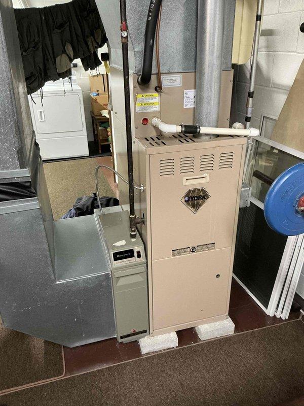 Conducted on-site evaluation of existing HVAC system in residential basement utility space for furnace and air conditioning replacement estimate. Assessed current beige furnace unit with blower assembly, photographed existing equipment configuration including ductwork routing, air handler components, and mechanical connections to document baseline conditions for replacement specifications.