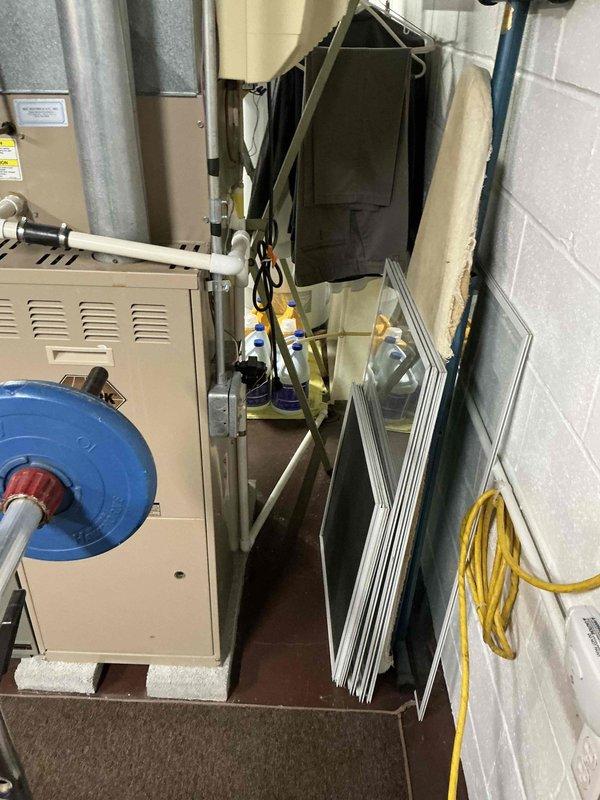 Conducted on-site evaluation of existing HVAC system in residential basement utility space for furnace and air conditioning replacement estimate. Assessed current beige furnace unit with blower assembly, photographed existing equipment configuration including ductwork routing, air handler components, and mechanical connections to document baseline conditions for replacement specifications.