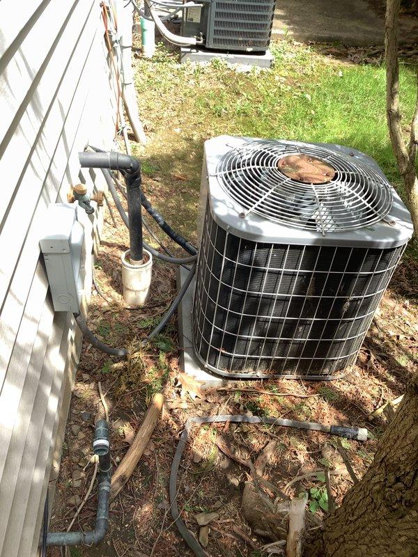 Performed comprehensive assessment of 25-year-old residential HVAC system showing significant age-related deterioration. Evaluated outdoor condensing unit with cylindrical design and indoor teal-colored Trane air handler with associated ductwork and condensate drainage system. Documented existing equipment condition through detailed photography, noting worn components and system configuration including refrigerant line routing, electrical disconnect, and PVC drain lines. Provided replacement estimate for complete system upgrade due to advanced age and declining performance of existing equipment.