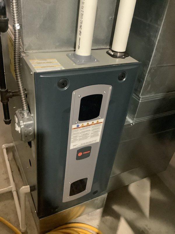 Performed comprehensive assessment of 25-year-old residential HVAC system showing significant age-related deterioration. Evaluated outdoor condensing unit with cylindrical design and indoor teal-colored Trane air handler with associated ductwork and condensate drainage system. Documented existing equipment condition through detailed photography, noting worn components and system configuration including refrigerant line routing, electrical disconnect, and PVC drain lines. Provided replacement estimate for complete system upgrade due to advanced age and declining performance of existing equipment.
