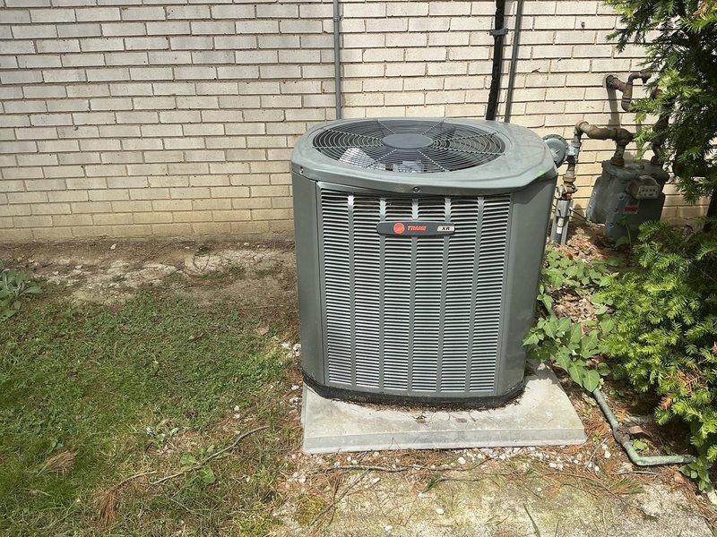 Completed estimate for air conditioning system replacement following exterior damage to existing 2014 condenser unit caused by lawn mower impact. Assessed damaged Trane condenser unit positioned on concrete pad against residential brick exterior, evaluated electrical disconnect and associated conduit connections, and documented current installation configuration including gas meter proximity and utility routing. Provided comprehensive replacement quote for new system installation to restore cooling capacity.