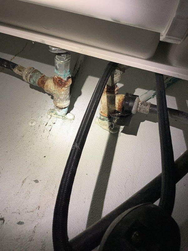 Responded to service call for non-functioning sump pump, dripping stationary tub valve, and mainline drainage issue. Upon inspection, discovered extensive corrosion and deterioration on shut-off valves beneath stationary tub, with heavy rust on metal fittings and valve bodies compromising operation. Documented significant turquoise-green corrosion and oxidation on insulated drainage pipes, with damaged white covering exposing degraded materials and rust staining on surrounding surfaces. Performed mainline snaking to clear drainage obstruction and restore proper flow.