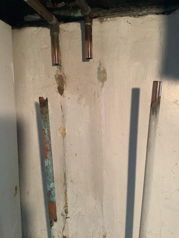Responded to service call for non-functioning sump pump, dripping stationary tub valve, and mainline drainage issue. Upon inspection, discovered extensive corrosion and deterioration on shut-off valves beneath stationary tub, with heavy rust on metal fittings and valve bodies compromising operation. Documented significant turquoise-green corrosion and oxidation on insulated drainage pipes, with damaged white covering exposing degraded materials and rust staining on surrounding surfaces. Performed mainline snaking to clear drainage obstruction and restore proper flow.
