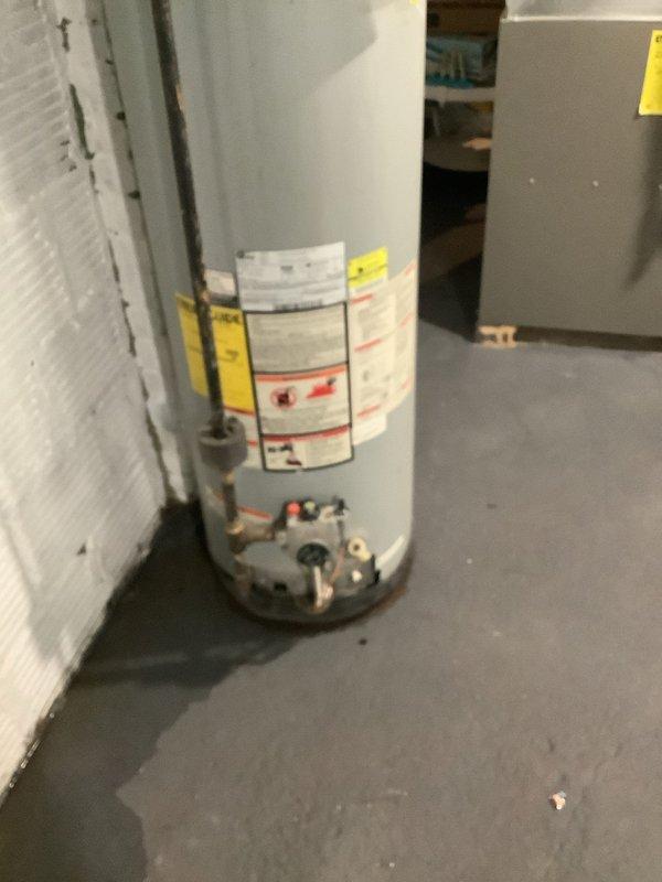 Responded to service call for leaking water heater. Upon inspection, found an American-brand tanked water heater showing visible signs of water leakage at the base with floor staining present. Unit is estimated to be over seven years old based on customer information. Evaluated overall condition of the water heater, including connections, pressure relief valve, and piping configuration. Documented current state with photographs showing the water heater installation, surrounding utility area, and evidence of moisture issues. Advised customer of findings and provided recommendation for water heater replacement due to age and active leak. Customer requested to be placed on cancellation wait list for expedited installation scheduling.