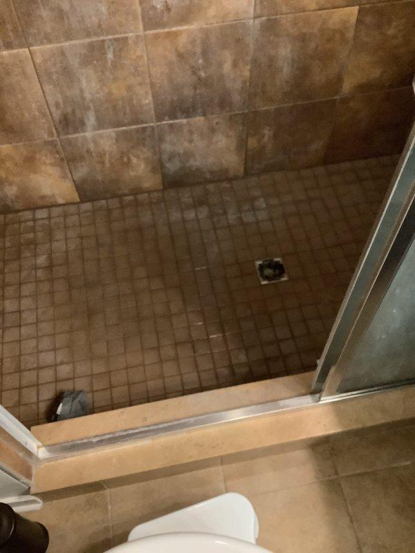 Responded to water leak originating from second-floor bathroom penetrating through ceiling into kitchen below. Conducted initial inspection and documented damage to kitchen ceiling, including displaced fluorescent light fixture and affected drywall. Assessed bathroom source area, examining shower enclosure with mosaic tile flooring and significant wall tile deterioration showing water staining and discoloration. Photographed existing conditions for restoration coordination. Service placed on hold pending completion of restoration company's work to allow for accurate repair quotation on secondary appointment.