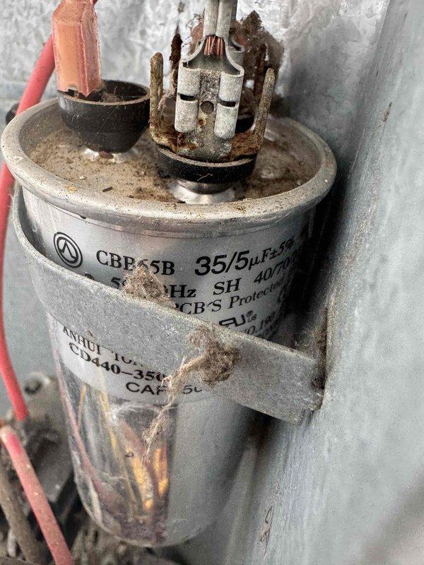 Responded to no cooling complaint on 5-year-old air conditioning system. Upon inspection, found failed dual run capacitor with severe corrosion on terminals and rust staining on capacitor body. Replaced defective capacitor with new unit, restored power to system, and verified proper operation of compressor and condenser fan motor. System now cooling normally.