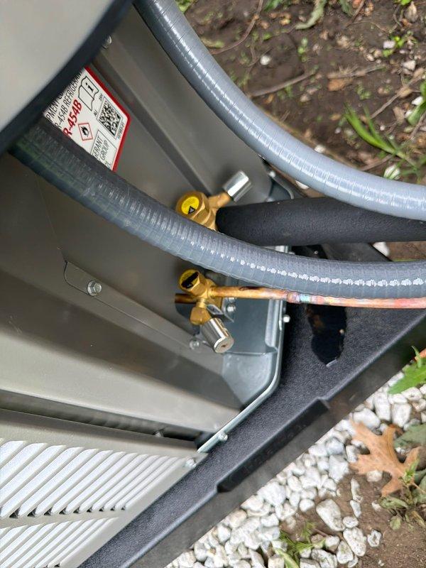 # HVAC Install - A/C & Coil

Successfully completed installation of new air conditioning system with evaporator coil. Installed outdoor condensing unit with proper refrigerant line connections using brass fittings and yellow service valves. Verified electrical connections and installed RNR 25 amp fuses in disconnect block for proper overcurrent protection. Routed flexible refrigerant lines through unit housing with secure connections at service valves. Unit positioned on white rock pad with proper clearances for airflow and service access. All electrical components properly terminated and secured. System ready for startup and commissioning.