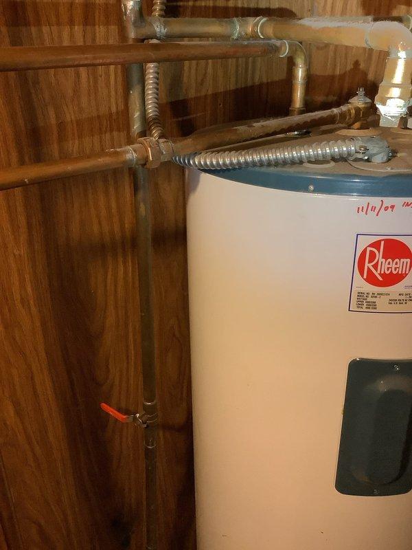 Responded to service call for 17-year-old Rheem water heater experiencing operational failure and unusual noises. Upon inspection, determined unit had reached end of serviceable life and required full replacement. Successfully removed old water heater and installed new Rheem residential tanked water heater unit, reconnecting all copper supply lines, brass fittings, and flexible connector hoses to existing plumbing infrastructure. Verified proper connections to overhead piping system, tested all valves for functionality, and ensured secure installation against wood-paneled utility room wall. System tested and restored to full operational status.