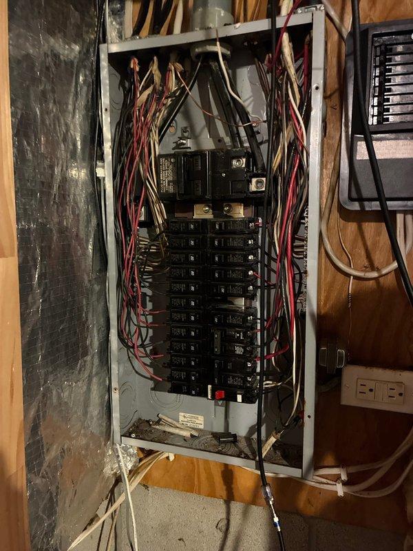 # Electrical Service Completed

Responded to service call for recurring breaker trip issues in a 1993-built residential property. Upon arrival, conducted comprehensive electrical system evaluation beginning with main service panel inspection in basement utility area.

Performed visual inspection of main electrical panel, identifying 24-30 circuit breakers arranged in dual vertical rows with main disconnect at top. Noted wire routing and connections throughout panel. Investigated potential overload conditions, loose connections, and signs of breaker degradation or heat damage at panel.

Extended troubleshooting to affected circuits throughout home. Located exposed junction box in living area with multiple branch circuits. Inspected wire connections, identified loose wire nuts on red, black, and white conductors. Removed outlet cover plate to access and evaluate receptacle connections and wire terminations.

Secured all loose connections within junction box using proper wire nuts. Verifi